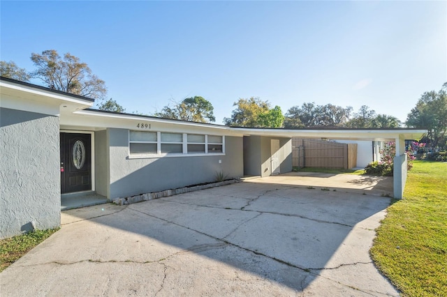 mid-century inspired home featuring stucco siding, an attached carport, and concrete driveway