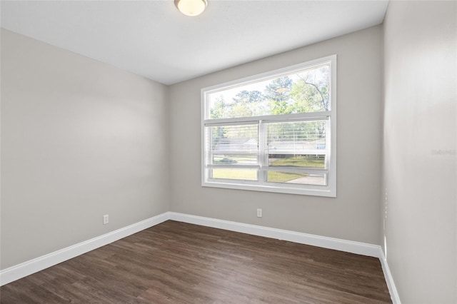 empty room with baseboards and dark wood-type flooring