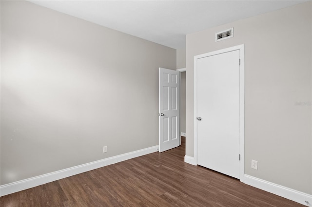 empty room featuring dark wood finished floors, baseboards, and visible vents