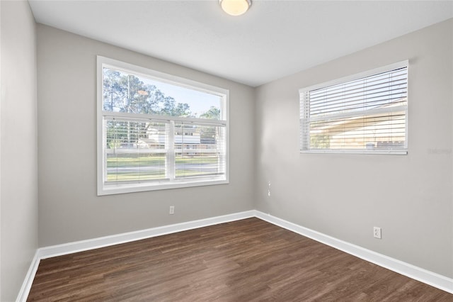 unfurnished room with baseboards and dark wood-style floors