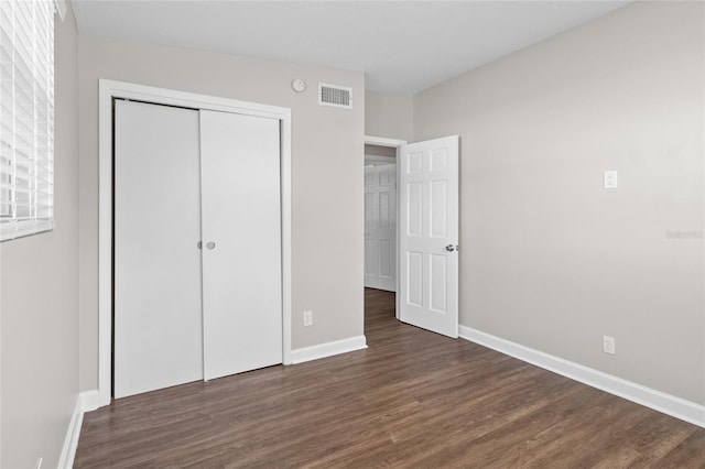 unfurnished bedroom with visible vents, baseboards, a closet, and wood finished floors