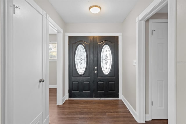 foyer with dark wood finished floors and baseboards