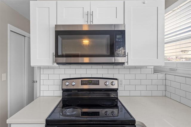 kitchen with decorative backsplash, appliances with stainless steel finishes, and white cabinetry