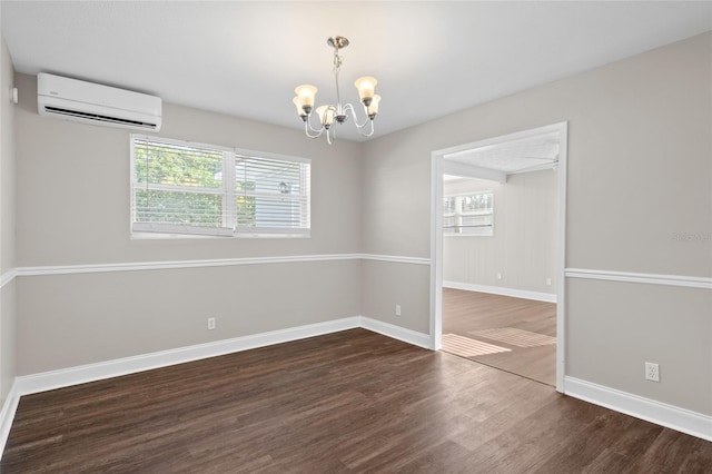 unfurnished room featuring a wall unit AC, wood finished floors, baseboards, and a chandelier