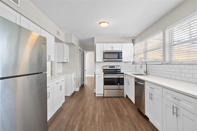 kitchen with visible vents, dark wood-type flooring, a sink, stainless steel appliances, and white cabinets