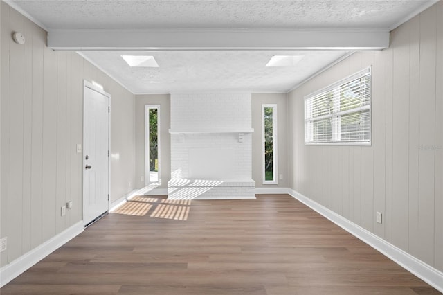 foyer entrance with a brick fireplace, a textured ceiling, baseboards, and wood finished floors