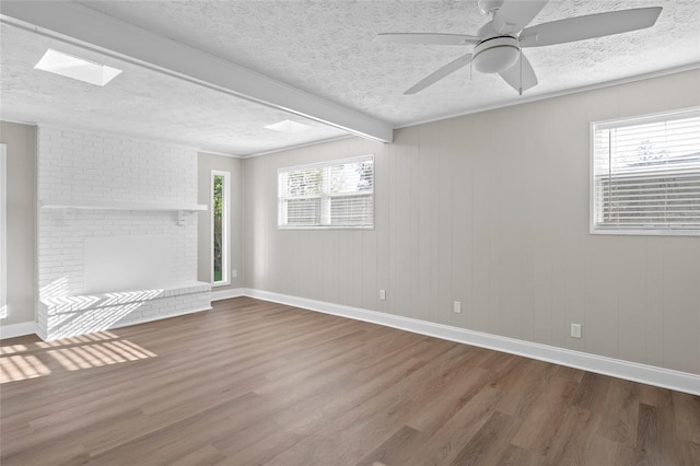 empty room with a healthy amount of sunlight, a textured ceiling, and wood finished floors