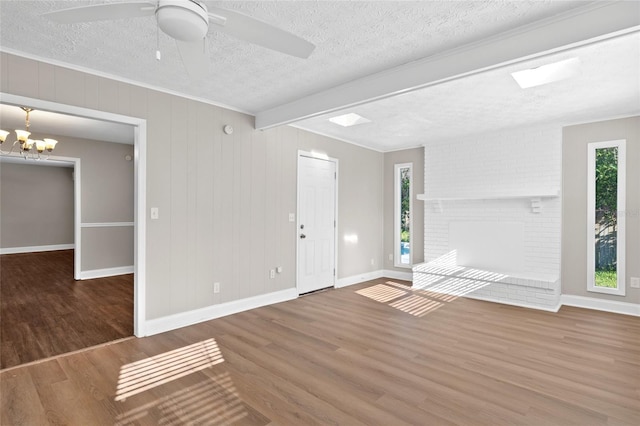 interior space featuring ornamental molding, ceiling fan with notable chandelier, a textured ceiling, wood finished floors, and baseboards