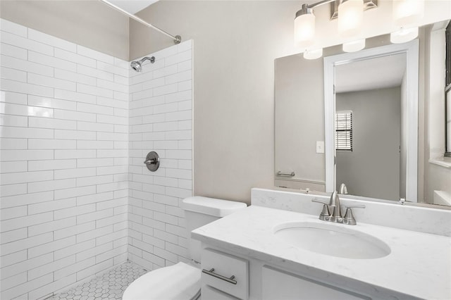 bathroom with vanity, toilet, and tiled shower