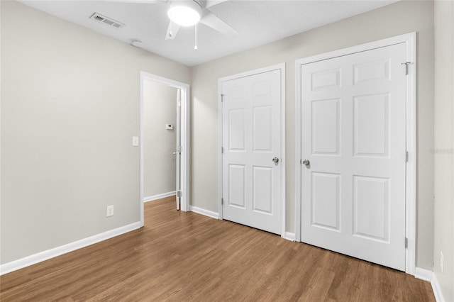 unfurnished bedroom featuring ceiling fan, wood finished floors, visible vents, and baseboards