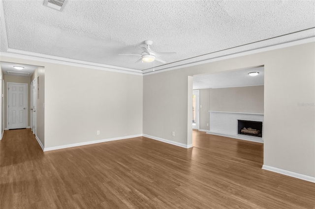 unfurnished living room with ceiling fan, visible vents, wood finished floors, and ornamental molding