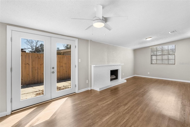 unfurnished living room featuring wood finished floors, visible vents, a fireplace, french doors, and a textured ceiling