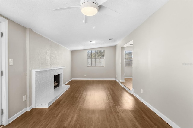 unfurnished living room with baseboards, a fireplace, wood finished floors, and a ceiling fan