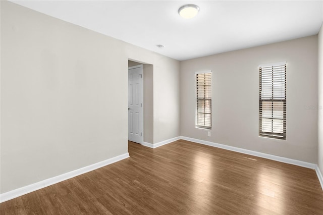 empty room featuring dark wood-style floors and baseboards