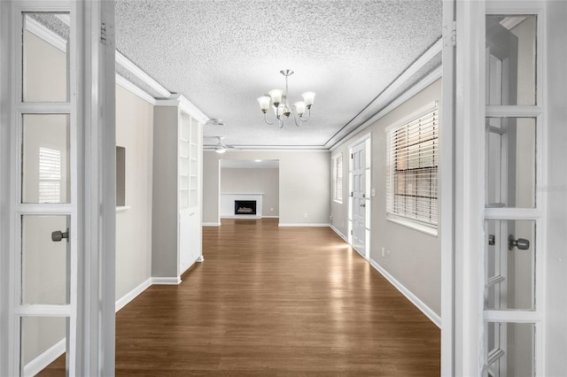 corridor featuring baseboards, dark wood finished floors, an inviting chandelier, ornamental molding, and a textured ceiling