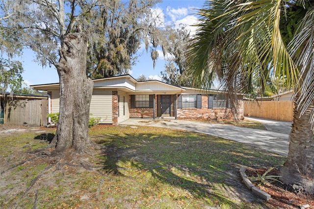 single story home featuring brick siding, driveway, and fence