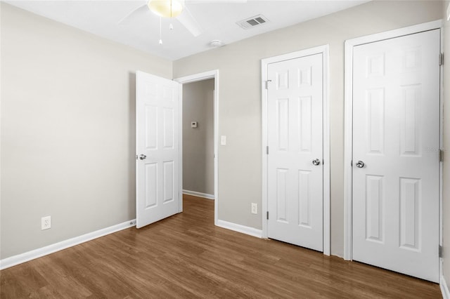 unfurnished bedroom featuring a ceiling fan, wood finished floors, visible vents, and baseboards