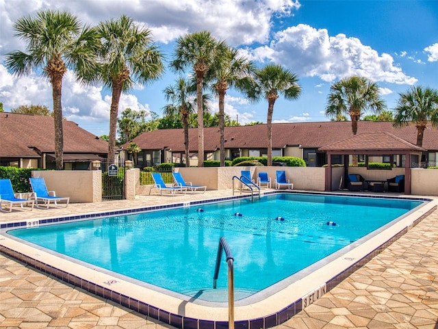 pool featuring a patio, fence, and a residential view