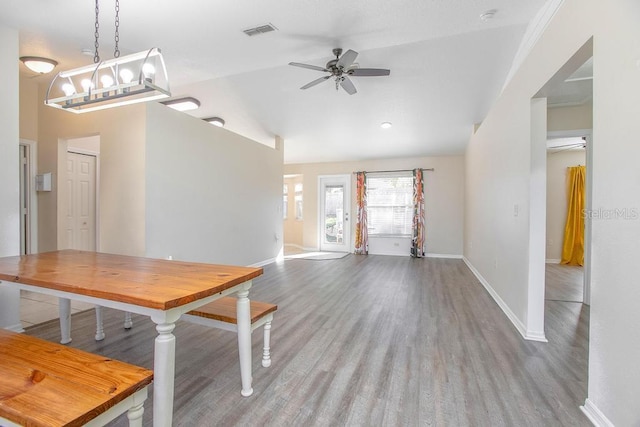 unfurnished dining area featuring wood finished floors, a ceiling fan, visible vents, baseboards, and lofted ceiling