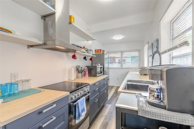 kitchen with light countertops, open shelves, island exhaust hood, light wood finished floors, and appliances with stainless steel finishes