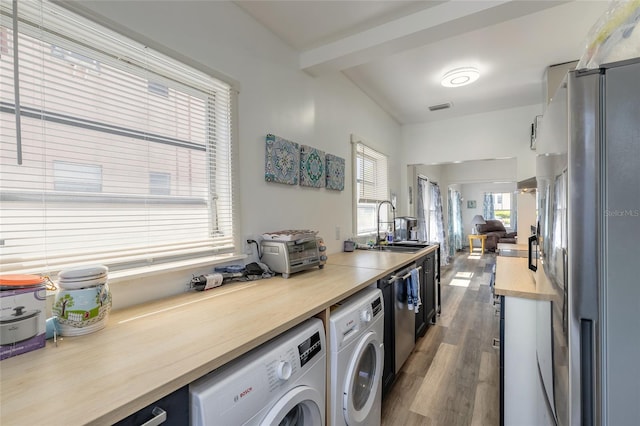 laundry room featuring visible vents, a sink, separate washer and dryer, and wood finished floors