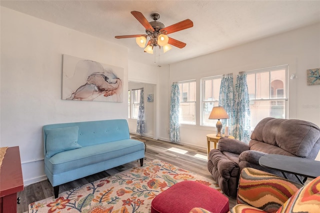 living room with baseboards, a wealth of natural light, wood finished floors, and a ceiling fan