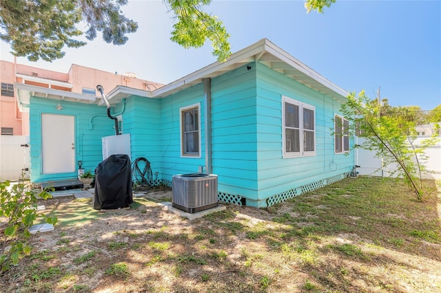rear view of house featuring a yard, crawl space, central AC, and fence