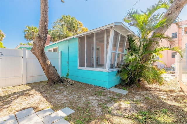 view of side of property with a sunroom and fence
