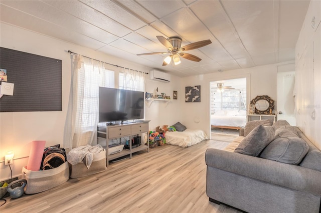 living area featuring wood finished floors, a wall unit AC, and a ceiling fan