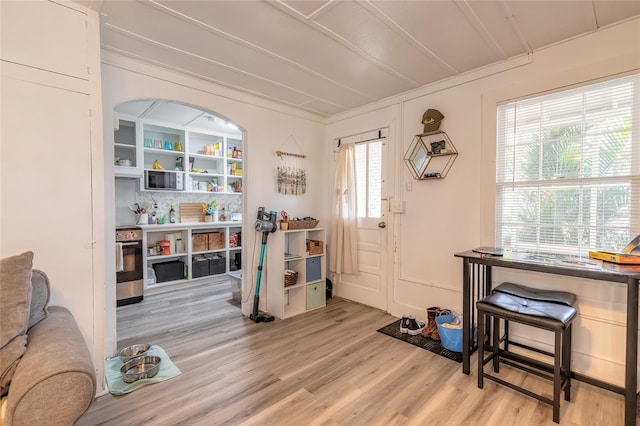 foyer with light wood finished floors and crown molding