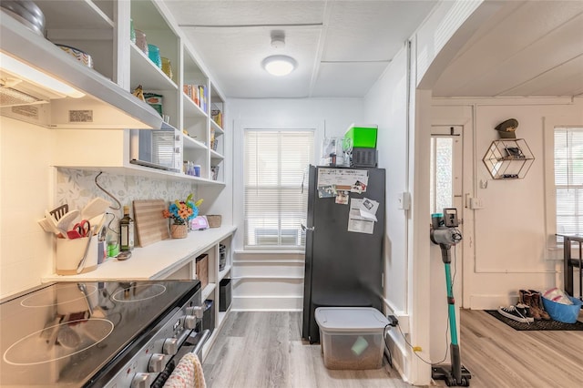 kitchen featuring light countertops, wood finished floors, open shelves, electric range, and freestanding refrigerator
