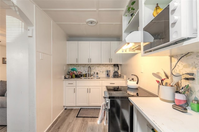 kitchen featuring electric stove, a sink, light countertops, and wall chimney range hood