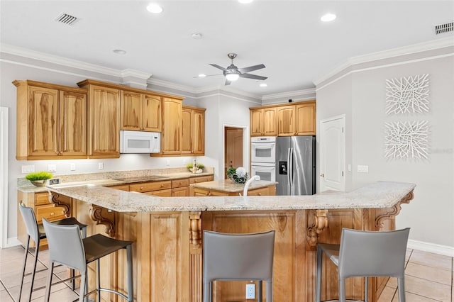 kitchen with visible vents, a kitchen island, black electric stovetop, white microwave, and stainless steel fridge