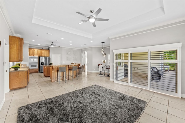 living area featuring a ceiling fan, a raised ceiling, and light tile patterned floors