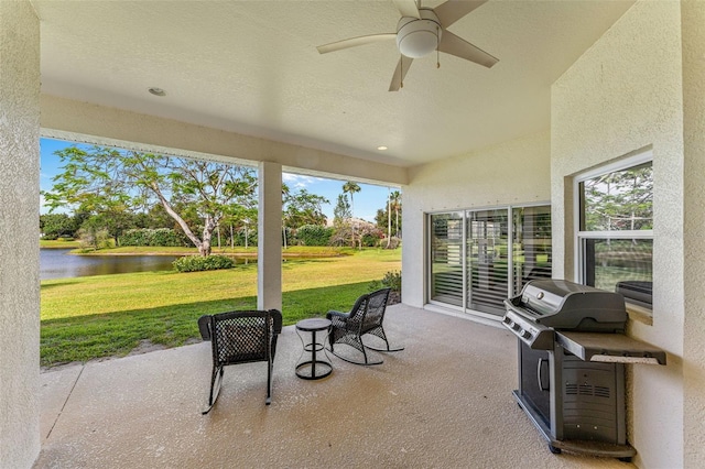 view of patio / terrace with a water view, a ceiling fan, and area for grilling