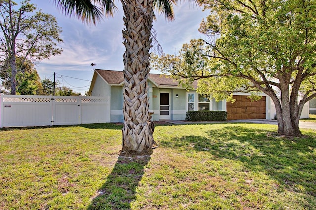 view of front facade featuring stucco siding, a garage, a front yard, and fence