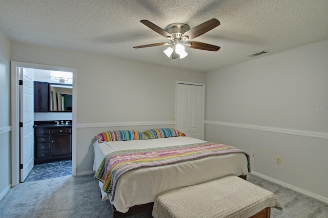 bedroom with a textured ceiling, carpet, visible vents, and connected bathroom