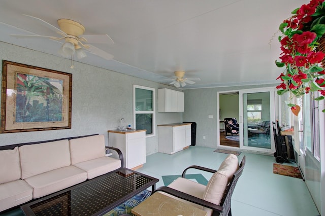 living area featuring a ceiling fan and a textured wall