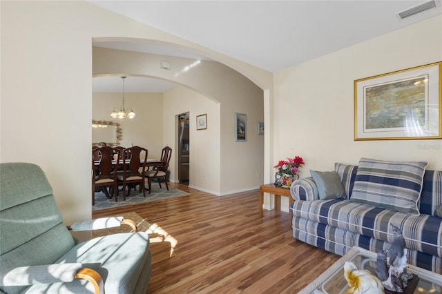 723 Pelican Ct, Kissimmee, FL 34759 - living area with visible vents, baseboards, wood finished floors, arched walkways, and a notable chandelier