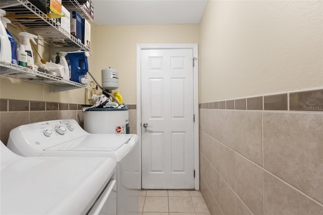 723 Pelican Ct, Kissimmee, FL 34759 - clothes washing area featuring washing machine and clothes dryer, water heater, laundry area, light tile patterned floors, and tile walls