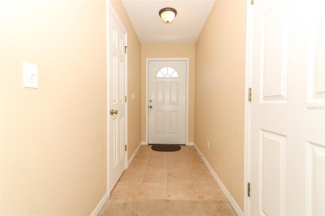 doorway with baseboards, light tile patterned floors, and light colored carpet