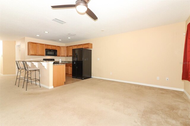 kitchen featuring a kitchen breakfast bar, visible vents, light carpet, and black appliances