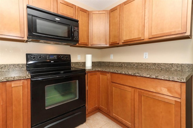 kitchen featuring light stone counters, light tile patterned floors, and black appliances