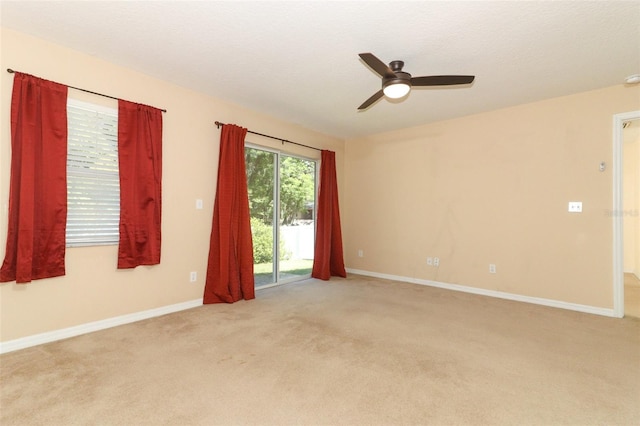 spare room featuring ceiling fan, light carpet, and baseboards