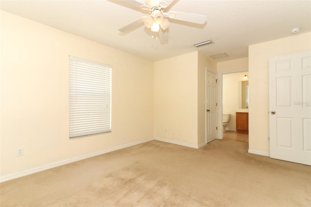 unfurnished bedroom featuring visible vents, light carpet, baseboards, ceiling fan, and connected bathroom
