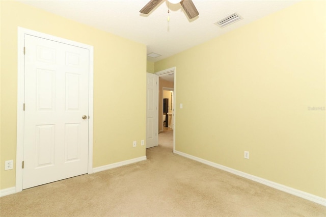 unfurnished bedroom featuring visible vents, baseboards, ceiling fan, and light colored carpet