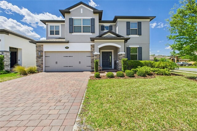 2090 Prairie Sage Ln, Longwood, FL 32750 - view of front of home with a front yard, stone siding, stucco siding, decorative driveway, and a garage