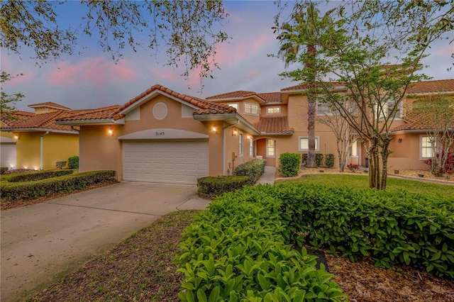 3145 Connemara Dr, Ormond Beach, FL 32174 - mediterranean / spanish house with stucco siding, a garage, a tiled roof, and concrete driveway