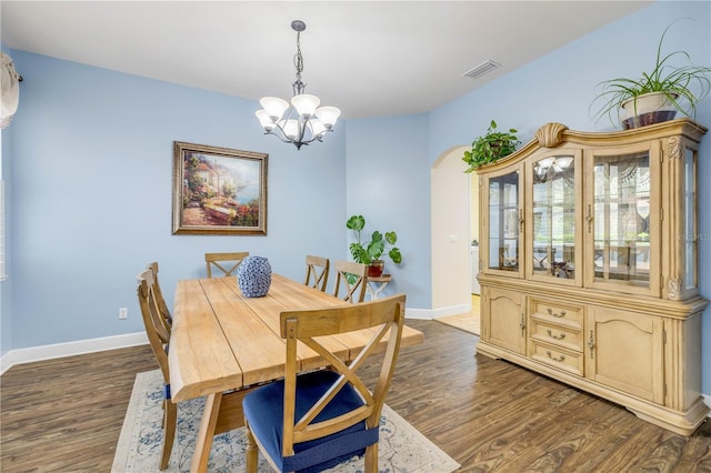3145 Connemara Dr, Ormond Beach, FL 32174 - dining space with arched walkways, a chandelier, dark wood-style floors, and baseboards