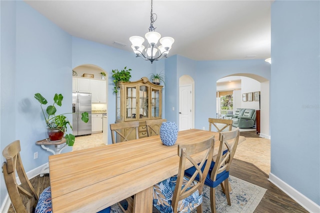 3145 Connemara Dr, Ormond Beach, FL 32174 - dining room featuring arched walkways, a chandelier, baseboards, and light wood-style floors